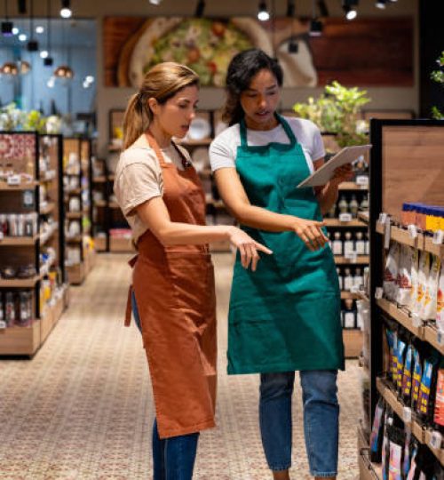 Latin American business manager training a new retail clerk at a supermarket - new job concepts